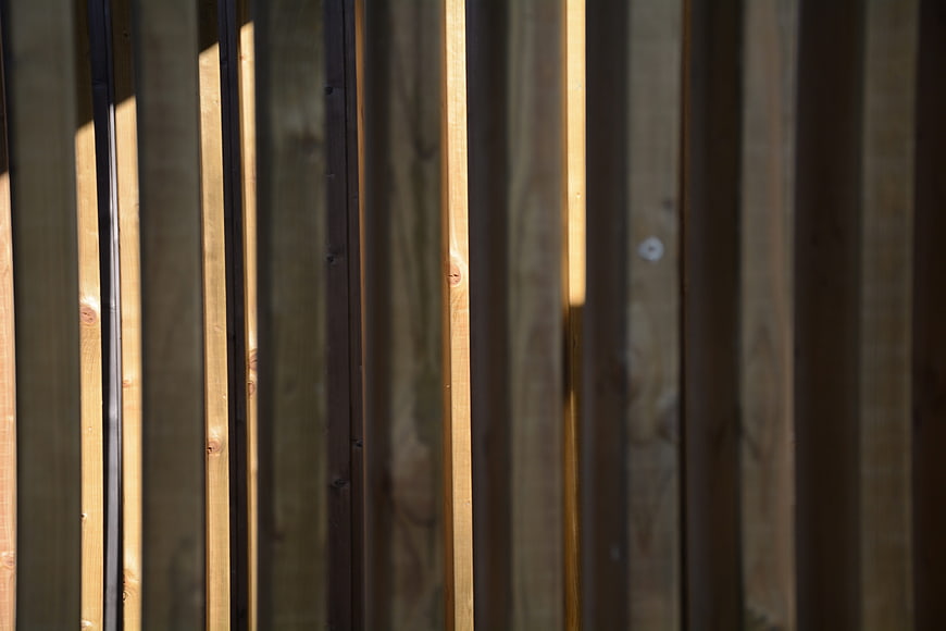 Vertical wooden fence planks with sunlight and shadows