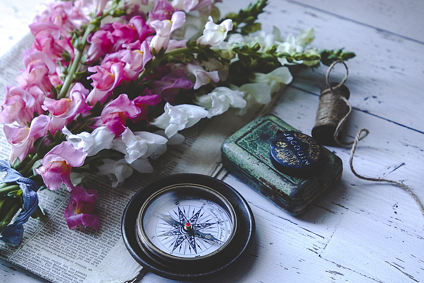 Vintage Compass and Pink Flowers on Rustic Wooden Table