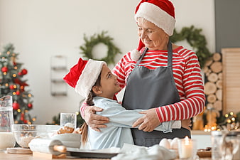 Grandmother and granddaughter hugging while baking Christmas cookies