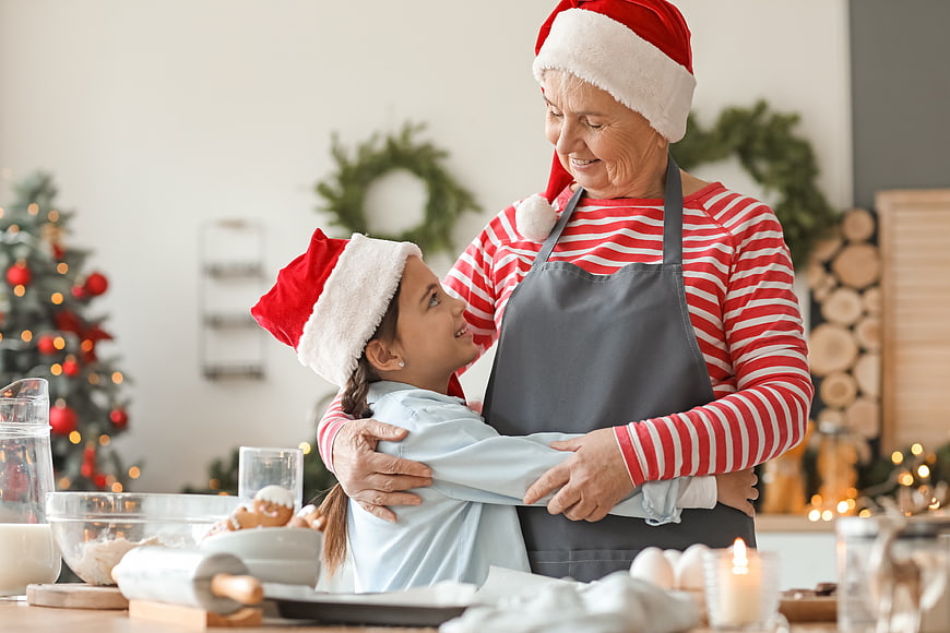 Grandmother and granddaughter hugging while baking Christmas cookies