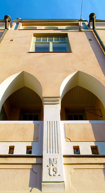 Low angle view of pastel yellow building facade with arches