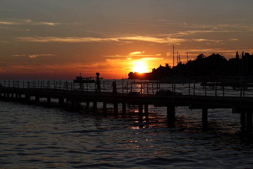 Silhouette of people on pier at sunset over water
