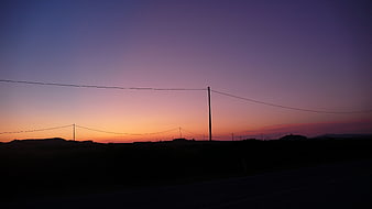 Silhouette of power lines against a colorful twilight sky