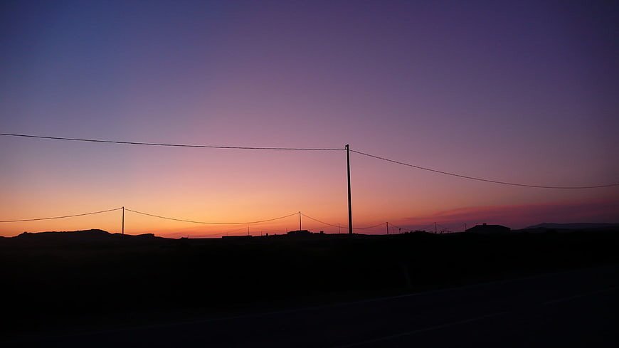 Silhouette of power lines against a colorful twilight sky