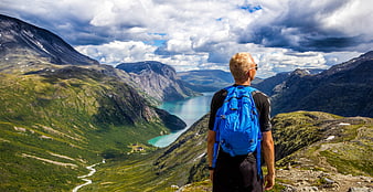 Hiker with Blue Backpack Overlooking Norwegian Mountain Fjord