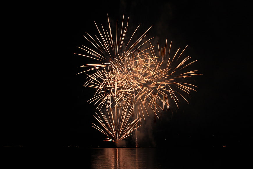 Golden Fireworks Display Over Dark Water At Night
