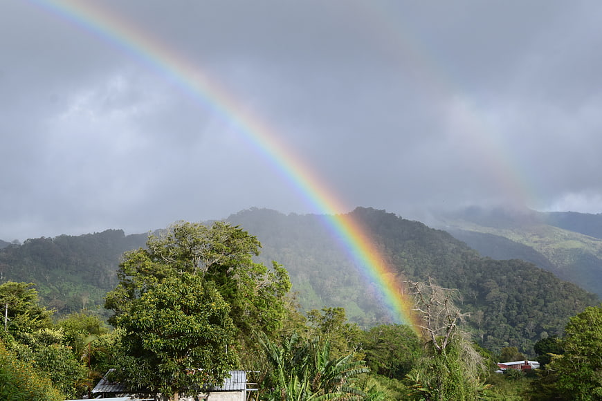 Vibrant Rainbow Arching Over Lush Green Mountain Landscape