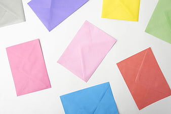 Colorful paper envelopes scattered on white background