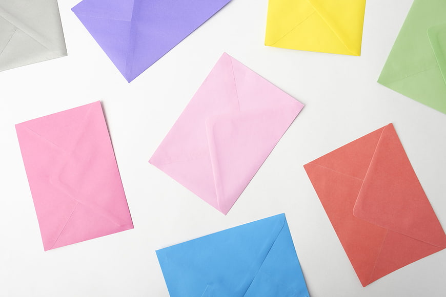 Colorful paper envelopes scattered on white background