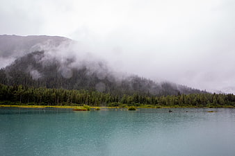 Misty turquoise lake with foggy mountain forest background