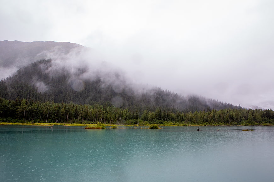 Misty turquoise lake with foggy mountain forest background