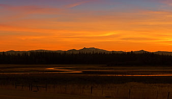 Vibrant Orange Sunset Over Mountain Range and River