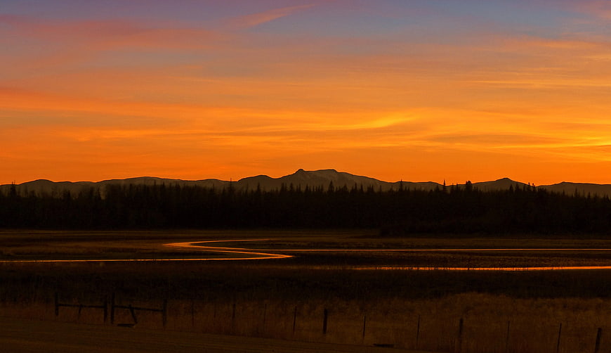 Vibrant Orange Sunset Over Mountain Range and River