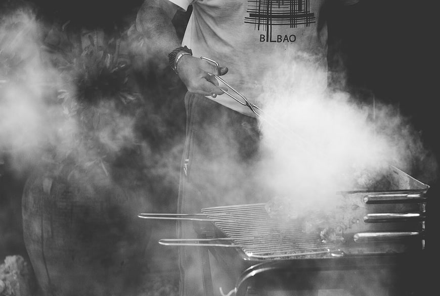Man Grilling Meat with Smoke in Black and White