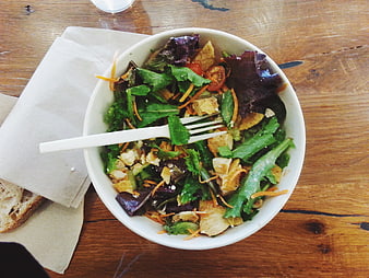 Overhead view of fresh mixed green salad in white bowl