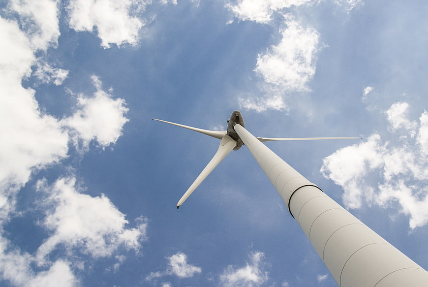 Low angle view of white wind turbine against blue sky