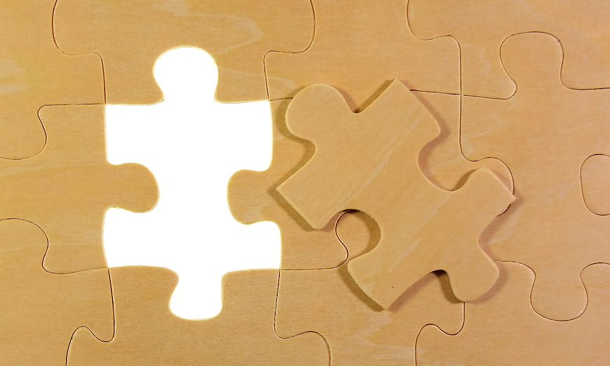 Wooden jigsaw puzzle with missing piece and bright white gap