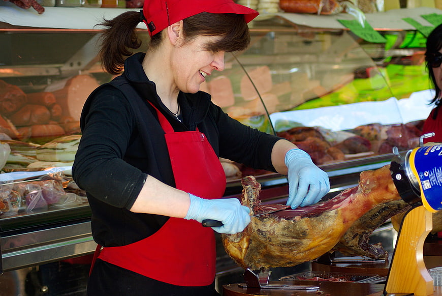 Woman slicing cured ham in a deli shop
