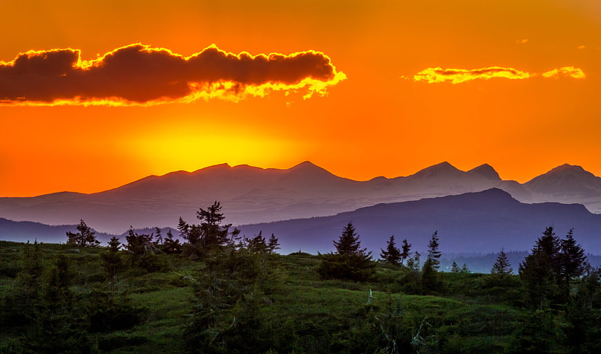 Dramatic Orange Sunset Over Mountain Ranges and Forest