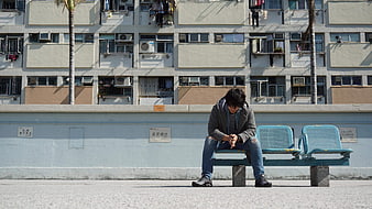 Lonely man sitting on bench in urban city street