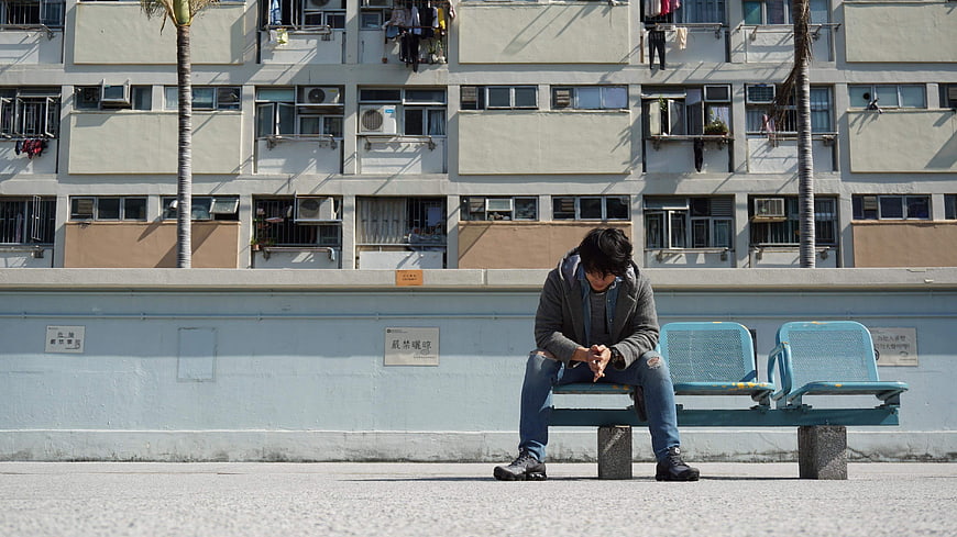 Lonely man sitting on bench in urban city street