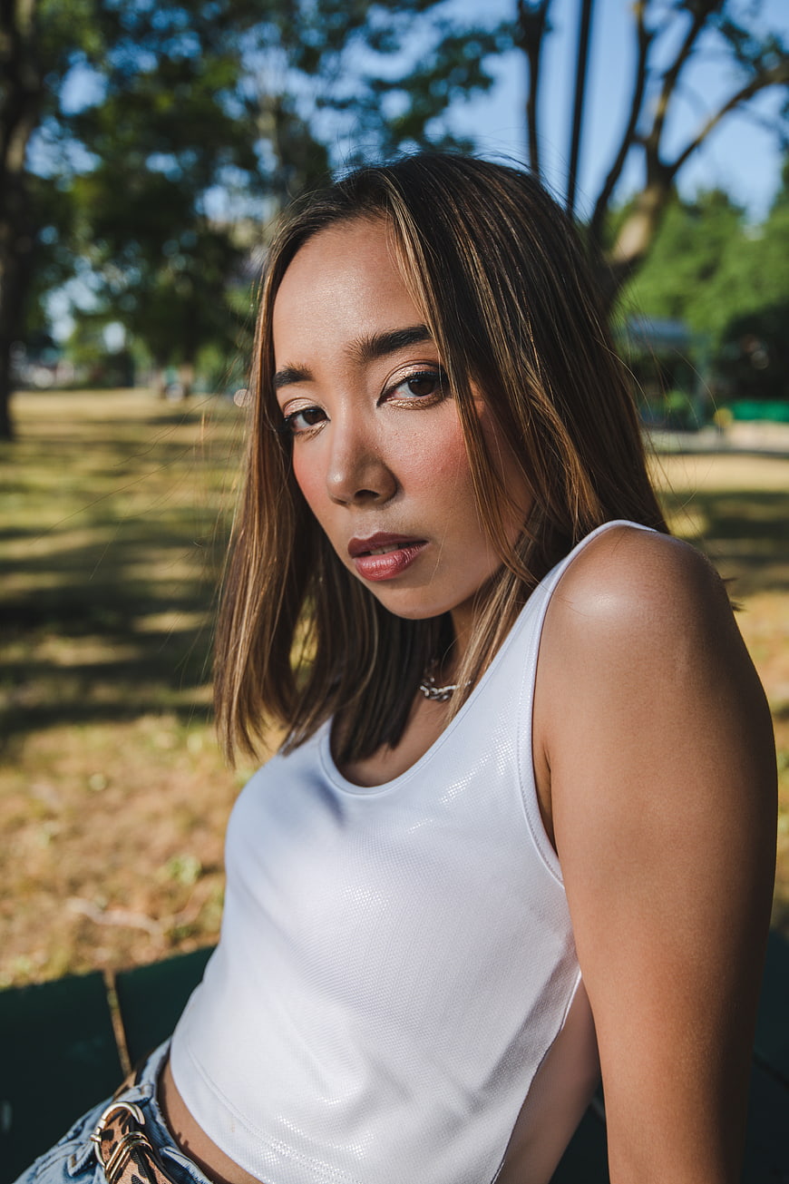 Portrait of young Asian woman in white tank top outdoors