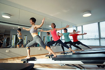 Group of women doing pilates reformer exercise in gym