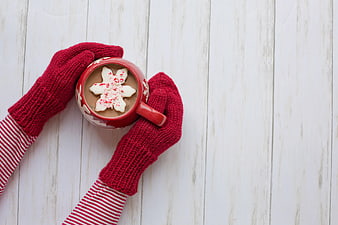 Cozy Red Mittens Holding Hot Chocolate with Snowflake on White Wood