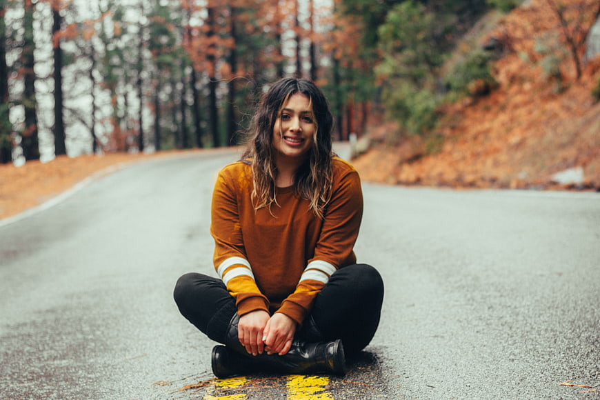 Woman sitting on road in autumn forest