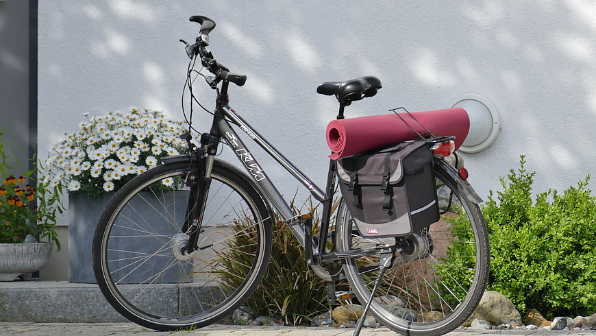 Mountain bike with yoga mat and pannier bag parked outdoors