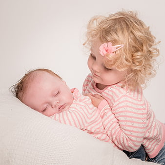 Tender Moment of Toddler Sister Caring for Sleeping Newborn Baby