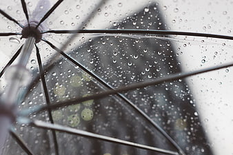 Raindrops on transparent umbrella with blurred city background