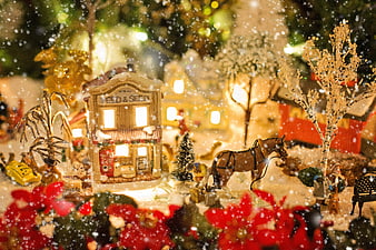 Illuminated Christmas Village Scene with Snow and Poinsettias