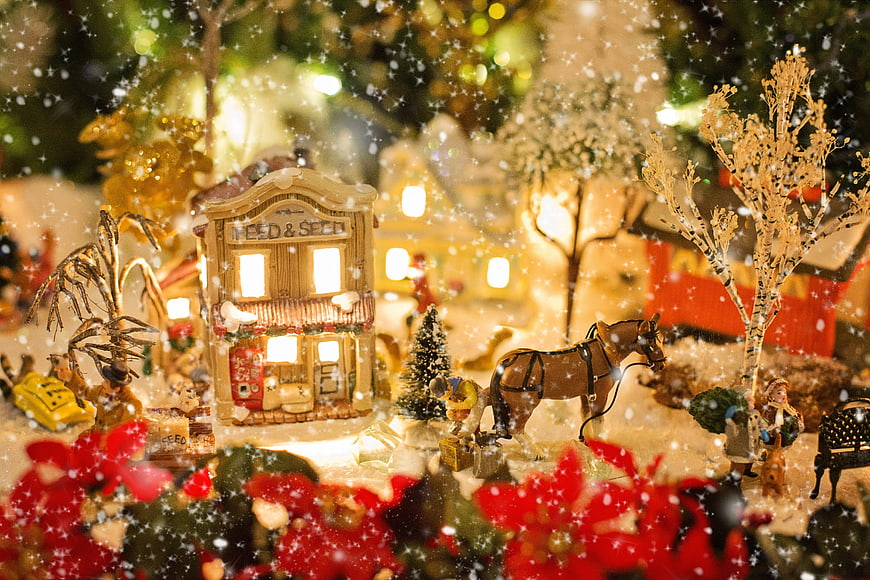 Illuminated Christmas Village Scene with Snow and Poinsettias