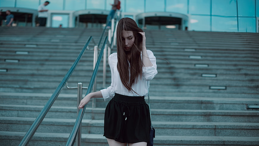 Stylish Young Woman in White Blouse and Black Skirt on Urban Stairs