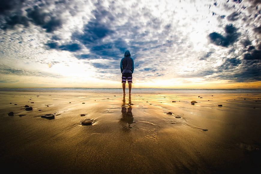 Lone Figure Standing on Beach at Sunset
