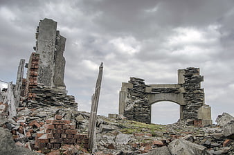 Ruins of an abandoned stone building under a cloudy sky