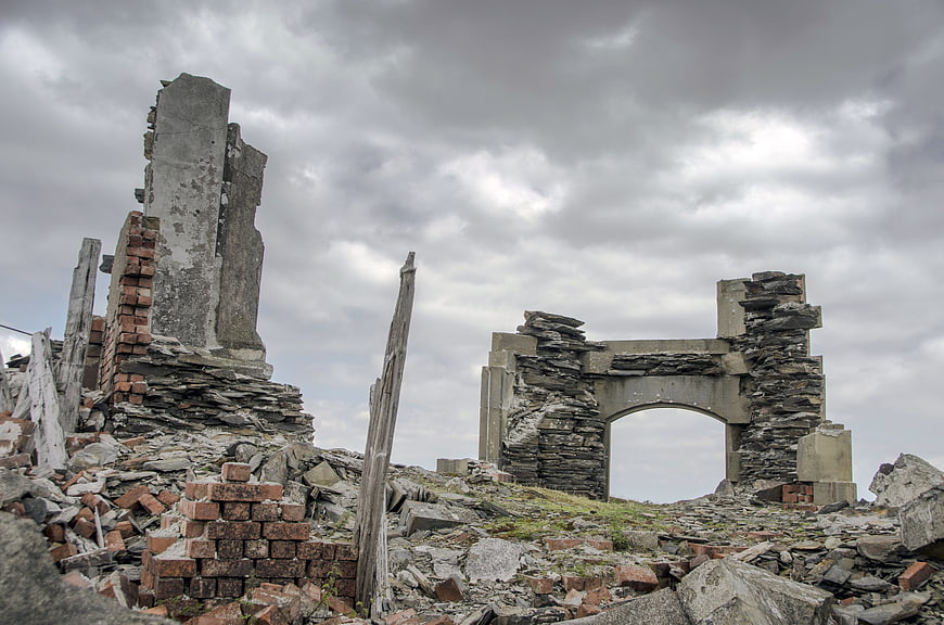 Ruins of an abandoned stone building under a cloudy sky