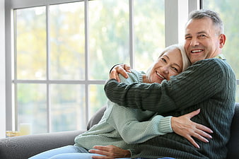 Happy Senior Couple Hugging on Sofa by Window