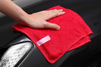 Hand Wiping Black Car Hood With Red Microfiber Cloth