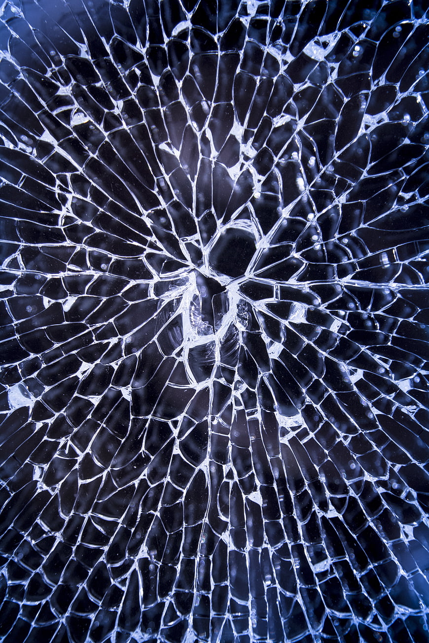 Close-up of shattered blue glass with radial cracks
