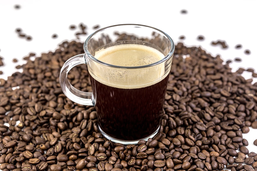 Glass Cup of Black Coffee on Roasted Coffee Beans
