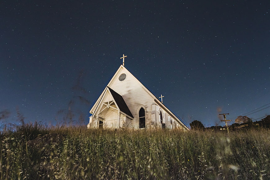 White Church Under Starry Night Sky in Grassy Field