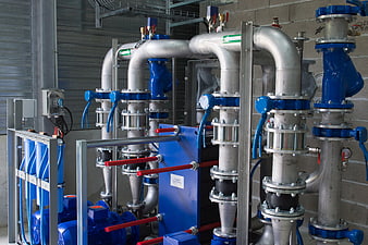 Industrial Water Filtration System With Blue Pumps And Silver Piping
