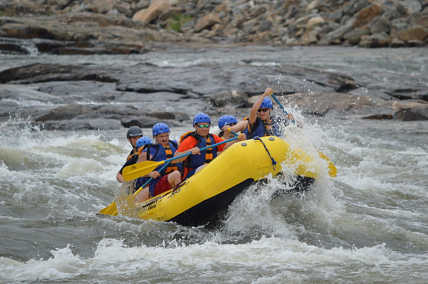 Group of people white water rafting in yellow raft