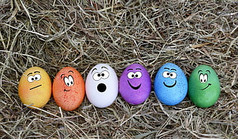 Colorful Easter eggs with cartoon faces on hay