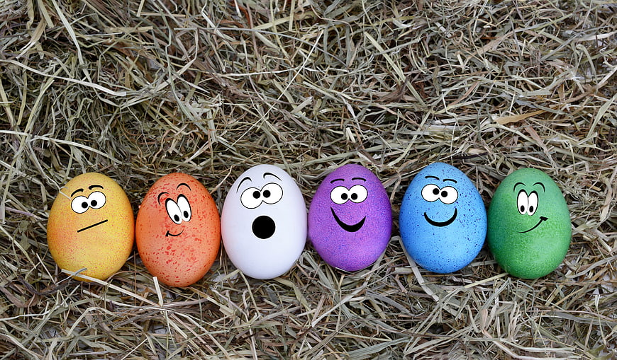 Colorful Easter eggs with cartoon faces on hay