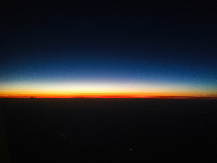 Aerial View of Vibrant Sunset Horizon Over Dark Ocean