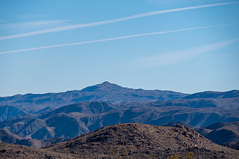Desert mountain landscape with blue sky and contrails