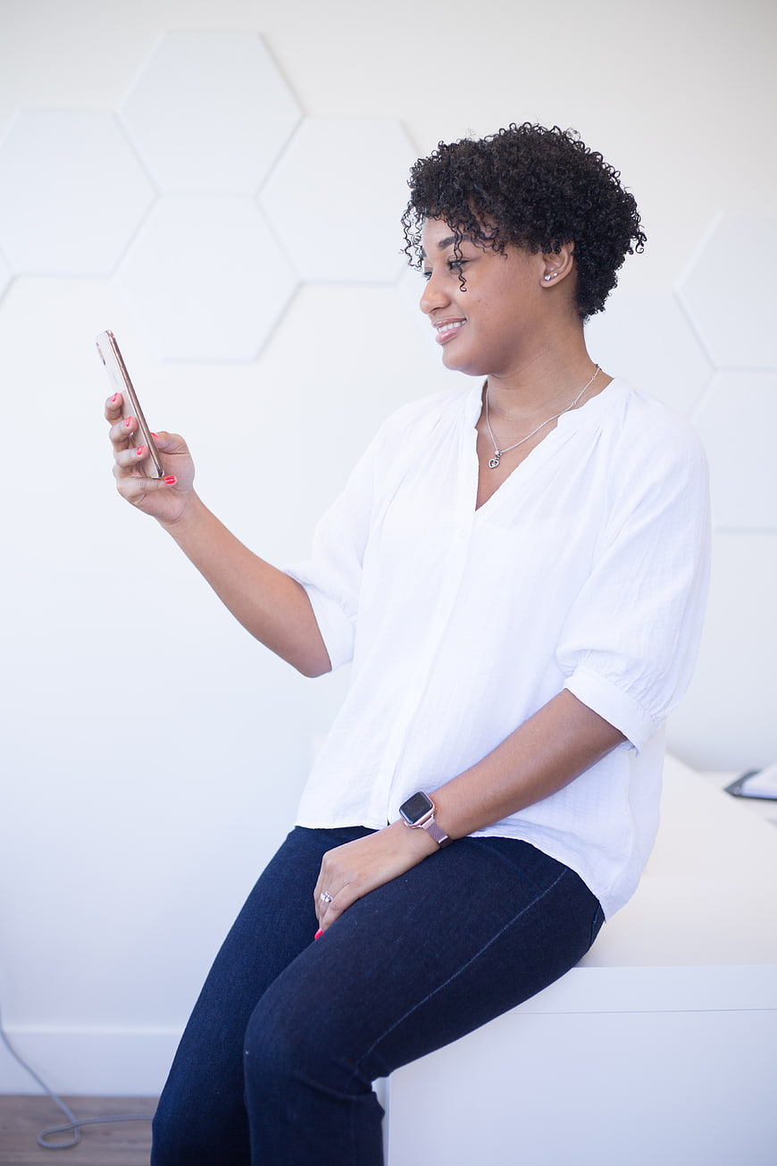 Smiling woman using smartphone in modern office